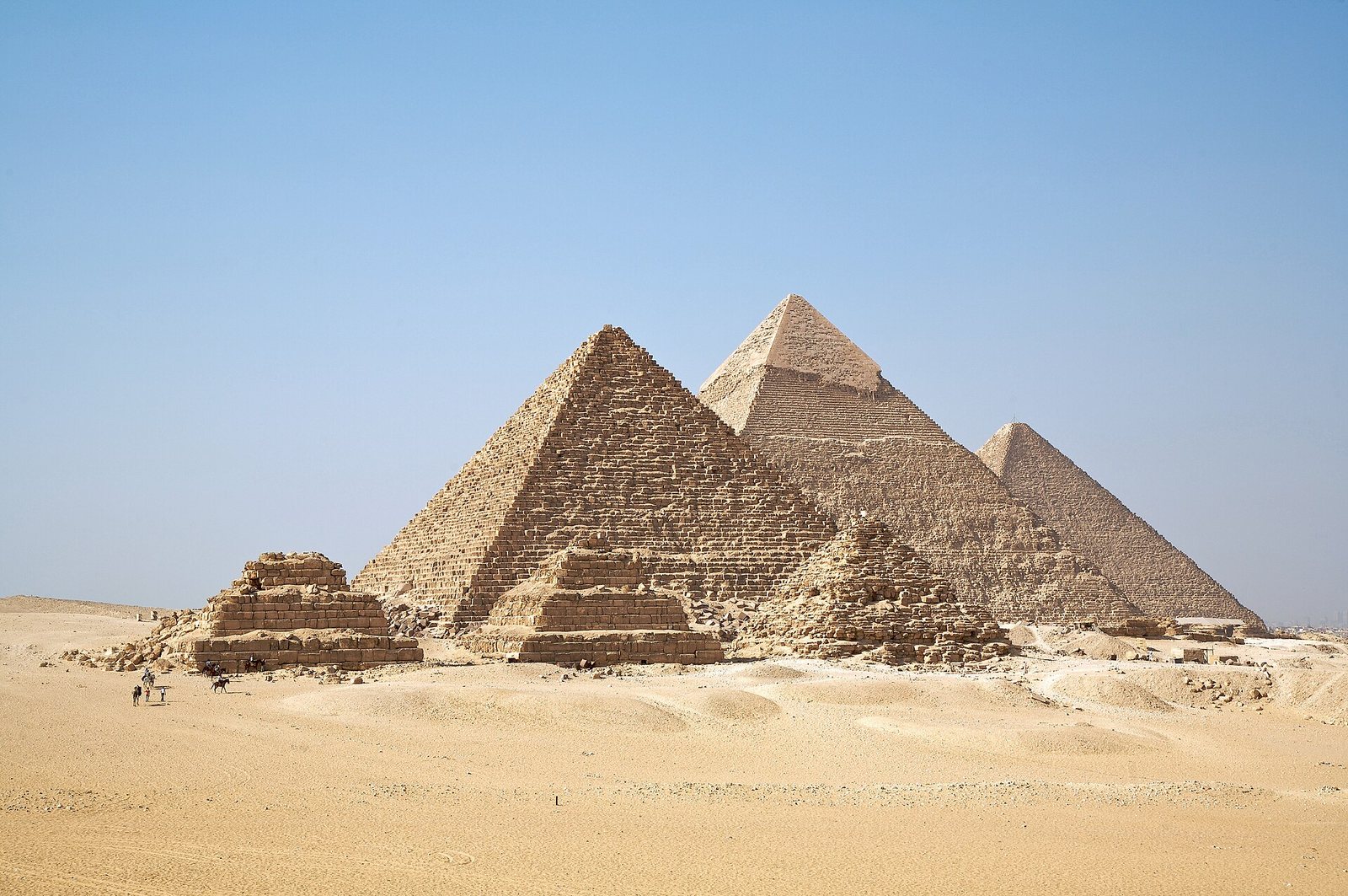The three pyramids of Giza in one photograph — Menkaure in front with its three satellite pyramids, Khafre with its casing cap, and Khufu behind
